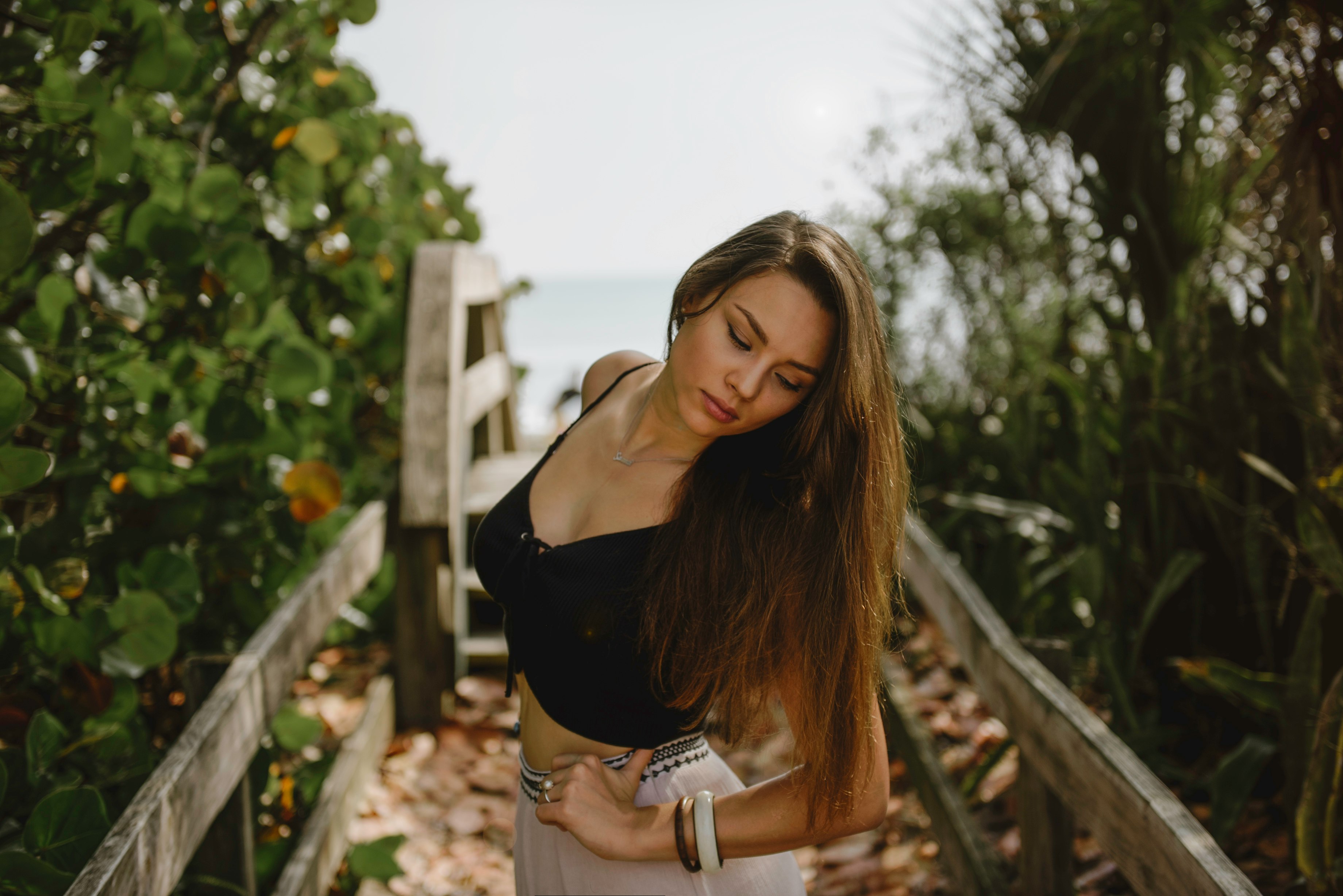 woman standing on bridge in between trees during daytime